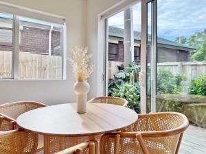 a table with chairs and a vase with flowers at Family Oasis 3BR vs Backyard Near Beach in Torbay in Auckland