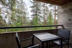 a table and chairs on a porch with a view of trees at Scandic Laajavuori in Jyväskylä