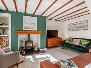 a living room with a green couch and a fireplace at 3 Bed in Cemaes 92812 in Llanfechell