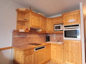 eine Küche mit Holzschränken und weißen Geräten in der Unterkunft Appartement Central 6 Pers, Parking, Ascenseur, Proche Pistes et Commerces - FR-1-572-22 in Les Carroz d'Araches