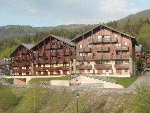 ein großes Gebäude mit einem Tennisplatz davor in der Unterkunft Appartement Central 6 Pers, Parking, Ascenseur, Proche Pistes et Commerces - FR-1-572-22 in Les Carroz d'Araches