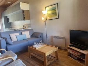 ein Wohnzimmer mit einem blauen Sofa und einem Fernseher in der Unterkunft Duplex lumineux 3 pièces, 7 pers, 3 balcons, proche pistes et commerces, parking, ski bus - FR-1-572-72 in Arâches-la-Frasse