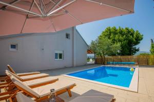 a swimming pool with chairs and an umbrella at Villa Velaria with private pool in Donja Glavina