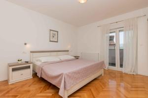 a white bedroom with a bed and a wooden floor at Villa Velaria with private pool in Donja Glavina +41 photos