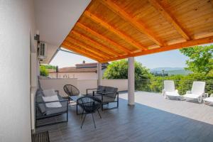 a patio with chairs and a wooden pergola at Villa Velaria with private pool in Donja Glavina