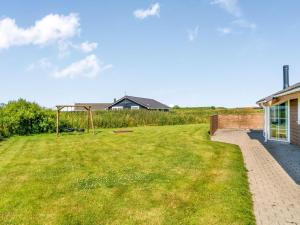 a grassy yard with a playground next to a house at Holiday Home Anya - 650m from the sea by Interhome in Løkken