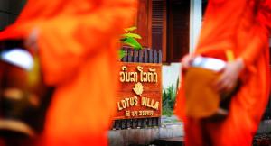 a person in orange robes standing in front of a plant at Lotus Villa in Luang Prabang