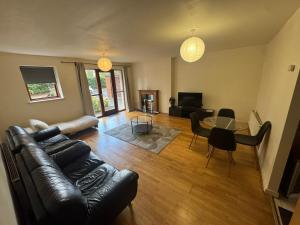 a living room with a leather couch and a table at Spacious 2-Bed Apartment Opposite Santry Park & 10 Min Away from Airport in Dublin