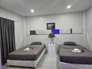 two beds in a hotel room with roses on them at Af พลูวิลล่า in Na Jomtien