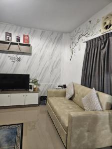 a living room with a couch and a television at Af พลูวิลล่า in Na Jomtien