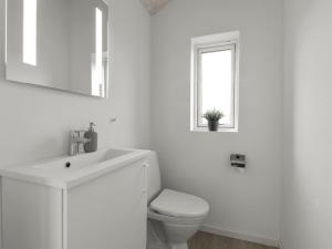 a white bathroom with a toilet and a sink at Holiday Home Dwerg - 1-5km from the sea by Interhome in Løkken