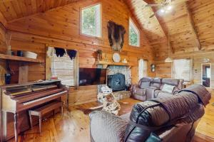 a living room with a couch and a piano in a cabin at Sunset Mountain Cabin in Ellijay