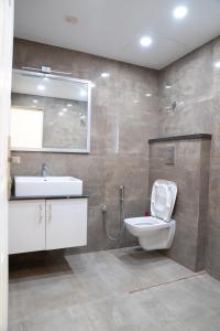 ein Badezimmer mit Toilette, Waschbecken und Spiegel in der Unterkunft Mayns Executive room -blue in Chennai