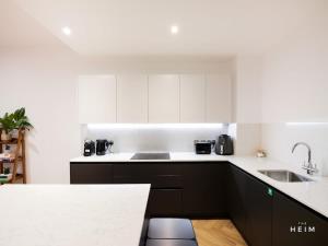 a kitchen with black and white cabinets and a sink at Shales at The Heim Residences in Manchester