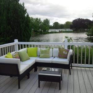 un sofá en una terraza con vistas al agua en Haggerston Lola the Lodge and Betty the Van en Cheswick