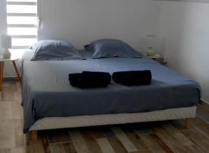 a bed with two black pillows on top of it at EDEN-RÉSIDENCE Le SAINT-BARTH Vue Mer et Piscine in Sainte-Luce