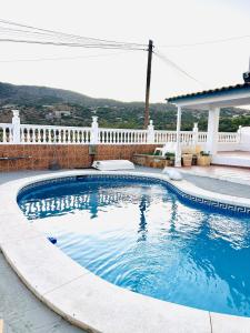 - une piscine dans une cour avec une clôture blanche dans l'établissement CASA RURAL MALAGA,VILLA FAMARA,10 personas,DESAYUNO ANDALUZ INCLUIDO EN EL PRECIO, à Malaga