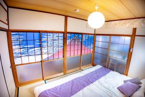 ein Schlafzimmer mit einem Bett in einem Zimmer mit Fenstern in der Unterkunft Voyager Inn in Tokio