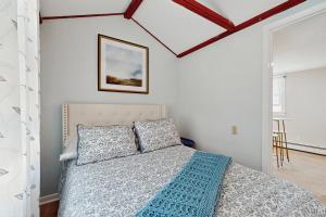 ein Schlafzimmer mit einem Bett mit einer blauen Decke in der Unterkunft Cape Breeze Cottage in Osterville