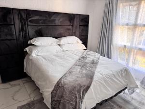a bedroom with a large bed with white sheets and pillows at Luxe spot in Johannesburg