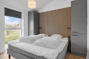 ein Schlafzimmer mit einem Bett mit weißen Laken und einem Fenster in der Unterkunft LN1998 Hirtshals - Birksvej 6 in Hirtshals