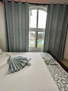 Una cama con un cisne en ella con una ventana en Kingsley apartments, en Malindi