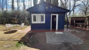 a blue shed with a white door in a yard at Relajante cabañita rodeada de bodegas in Ciudad Lujan de Cuyo