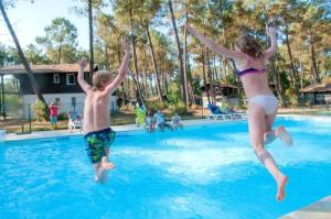 a boy and a girl jumping into a swimming pool at Villa haut de gamme 11 personnes jacuzzi privé in Lacanau