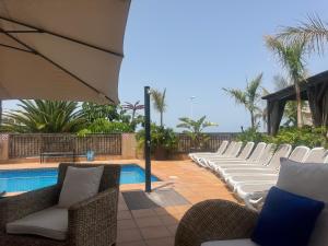 a row of chairs sitting next to a swimming pool at VILLA BLOSSOM in the beautiful area of Puerto Santiago Tenerife with 5 bedrooms for up to 10 guests private swimming pool and many other activities to entertain the family Secure parking for 2 cars and disabled access throughout in Puerto de Santiago