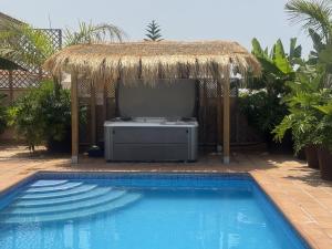 a swimming pool with a hut with a television in it at VILLA BLOSSOM in the beautiful area of Puerto Santiago Tenerife with 5 bedrooms for up to 10 guests private swimming pool and many other activities to entertain the family Secure parking for 2 cars and disabled access throughout in Puerto de Santiago