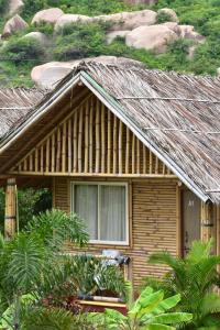 a house with a thatched roof with a window at Mowgli's Cafe Hampi & Guest House in Hampi