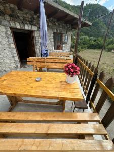 a wooden picnic table with flowers and an umbrella at GUEST HOUSE “ Center Theth “ in Theth