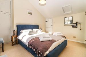 a bedroom with a large bed with a blue headboard at Quaint 2 bed cottage near North Norfolk Coast - Harpers Cottages in Syderstone