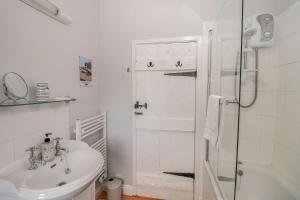 a white bathroom with a sink and a shower at Quaint 2 bed cottage near North Norfolk Coast - Harpers Cottages in Syderstone +25 photos
