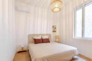 una camera bianca con un letto con due cuscini di Chaleureuse maison en centre ville a Perpignano