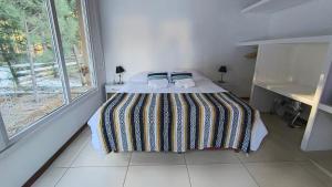 a bed in a white room with a window at Morada entre Valles in San Carlos de Bariloche