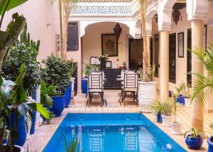 une cour avec une piscine, des chaises et des plantes dans l'établissement Riad Tala, à Marrakech
