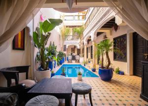 une piscine dans un immeuble avec des plantes et une table dans l'établissement Riad Tala, à Marrakech