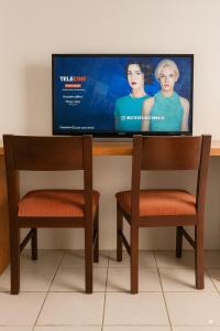 two chairs in front of a tv with a tv screen at Maestro in Fortaleza