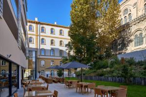 Un patio con mesas y sillas frente a un edificio. en Zenao Appart'hôtels Marseille Prado, en Marsella