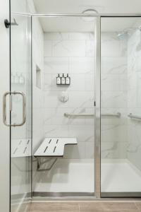 a glass shower door with a bench in a bathroom at Mint House Nashville - Marathon Village in Nashville +34 photos