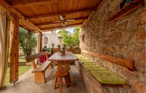 a patio with a wooden table and bench and a stone wall at Gorgeous Apartment In Karlobag With Wifi in Karlobag