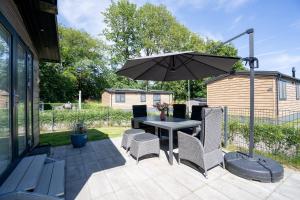 シャルボイツにあるOstseecamp Ferienhaus "Karin"のテーブルと椅子と傘のあるパティオ