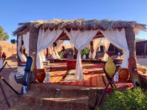 a tent with a thatched roof in the desert at Desert Bivouac Mhamid in Mhamid