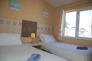 two beds in a room with a window at Morannedd Lodge Barmouth Bay in Llanddwywe