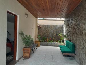 a patio with a green chair and a stone wall at Casa Grande da praia de Piratininga in Niterói