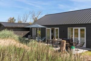 a black house with a table and chairs at LN1985-Hjorring-Kystvejen-125 in Hjørring