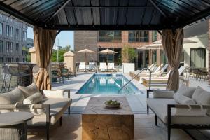 a patio with a swimming pool and tables and chairs at Mint House Nashville - Marathon Village in Nashville