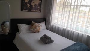 un letto con due sacchi sopra con una finestra di Rhodesfield's Hidden Gem a Kempton Park Altre 6 foto