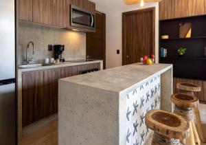 a kitchen with a kitchen island with two stools at Ideal Location with Cenote Pools Gym Restaurant in Tulum